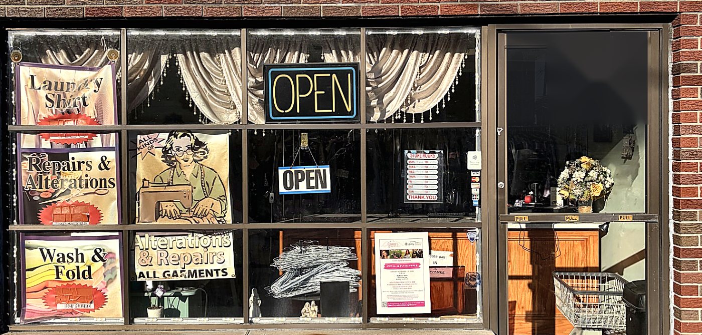 Front window of Anna Simone Dry Cleaners with Open signs and posters for Wash & Fold, Laundry Shirts, and Alterations & Repairs